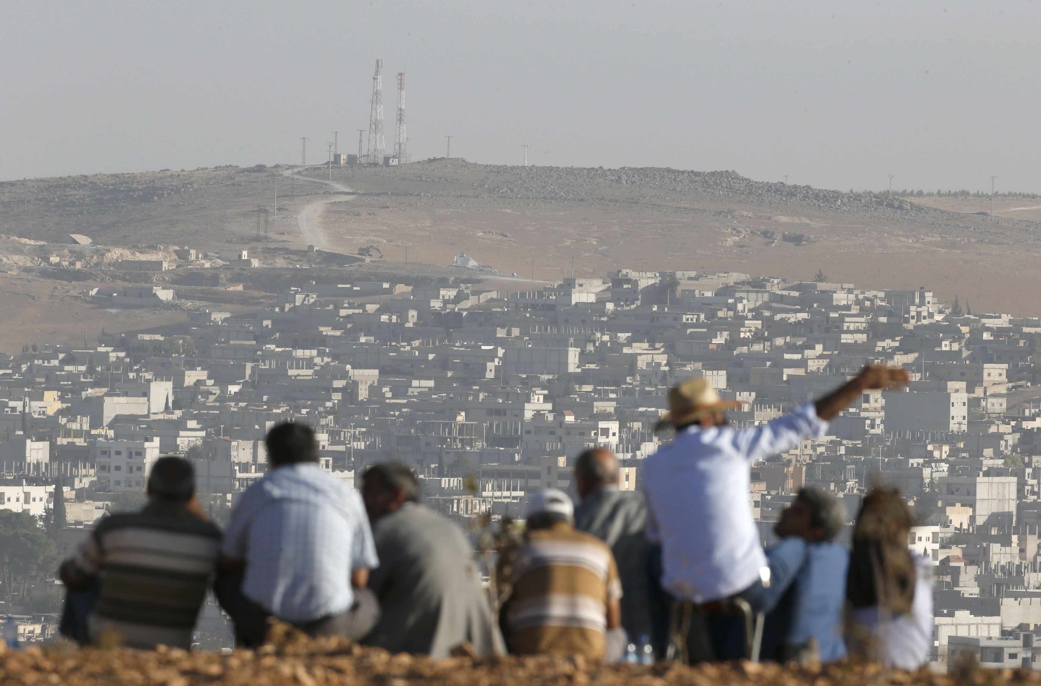 Turkish Kurds look towards the Syrian Kurdish town of Kobani from the top of a hill close to the border line between Turkey and Syria near Mursitpinar- Umit Bektas, Reuters