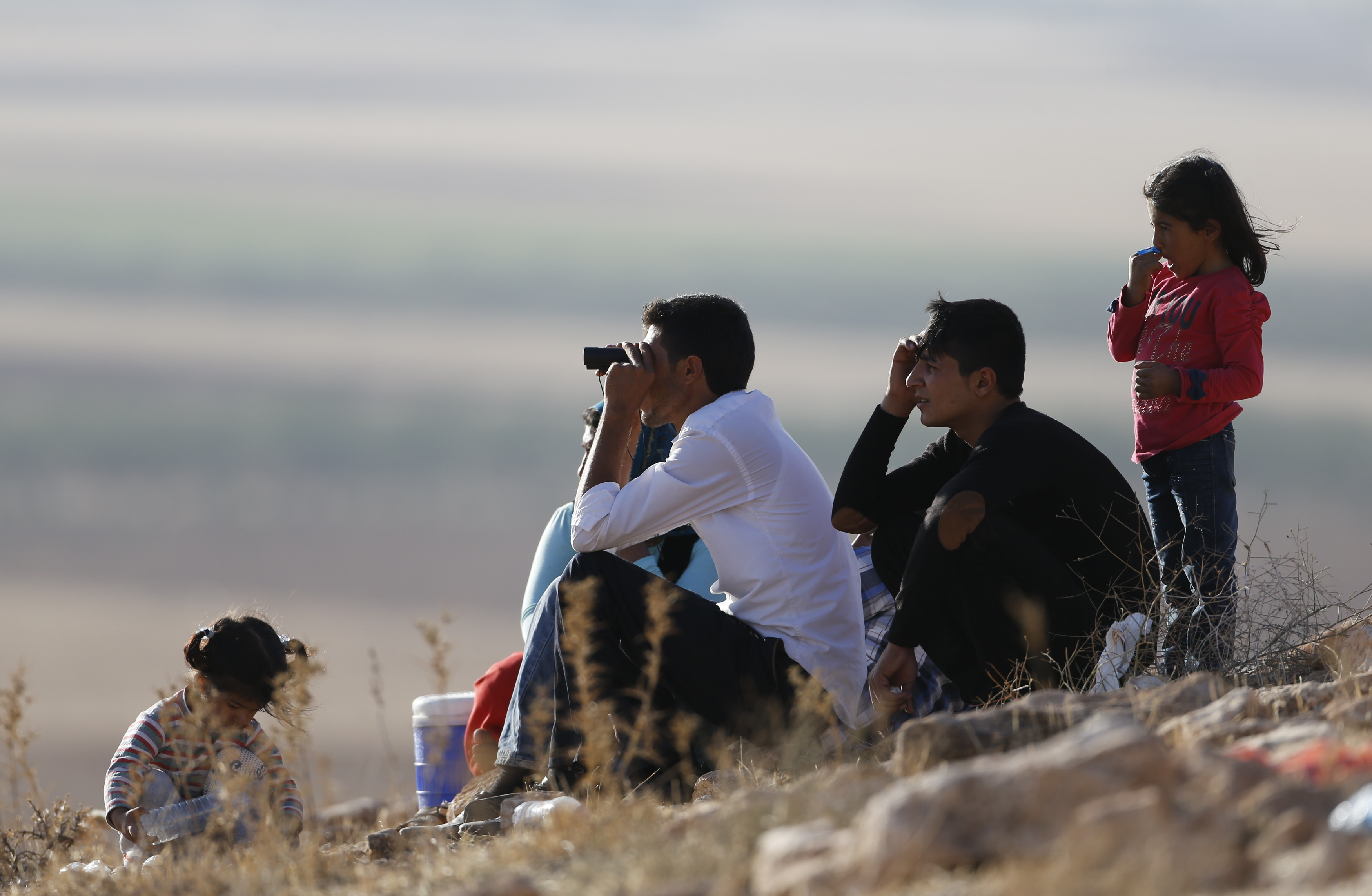 Turkish Kurds look towards the Syrian Kurdish town of Kobani from the top of a hill close to the border line between Turkey and Syria near Mursitpinar-Umit Bektas, Reuters